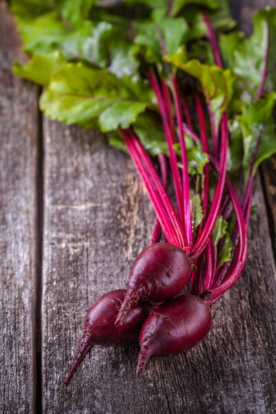 Young beet with tops on a wooden background, vertically, copyspace