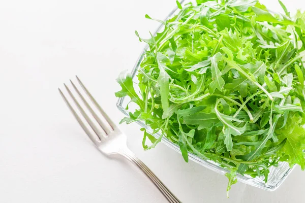 Зеленый салат в стеклянной чашке на белом столе — стоковое фото