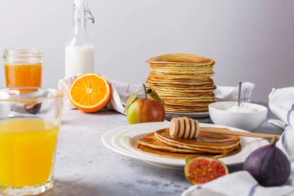 Panqueques con miel, fruta y café sobre un fondo gris — Foto de Stock