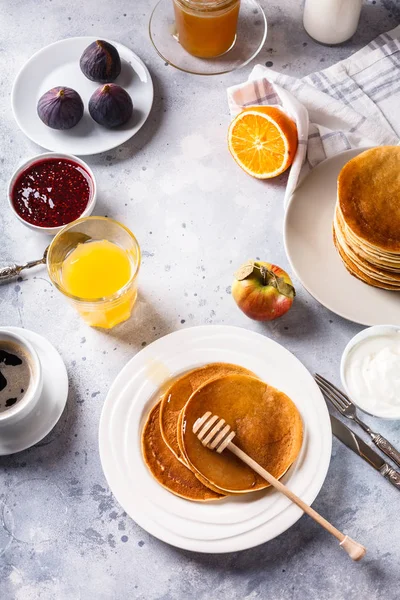 Pancakes with honey, fruit and coffee on a gray background — Stock Photo, Image
