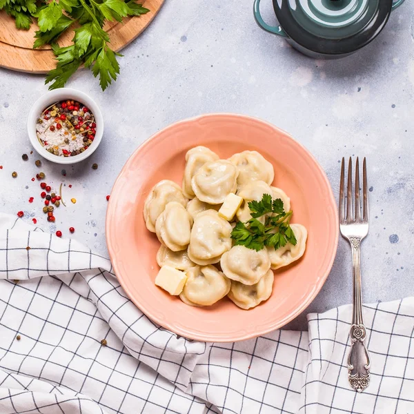 Bir gri arka plan, maydanoz, kare gri bir tabağa haşlanmış köfte