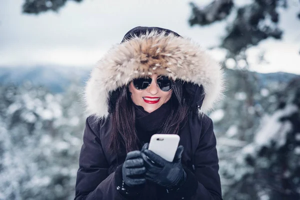 Beautiful woman with mobile phone snow landscape.