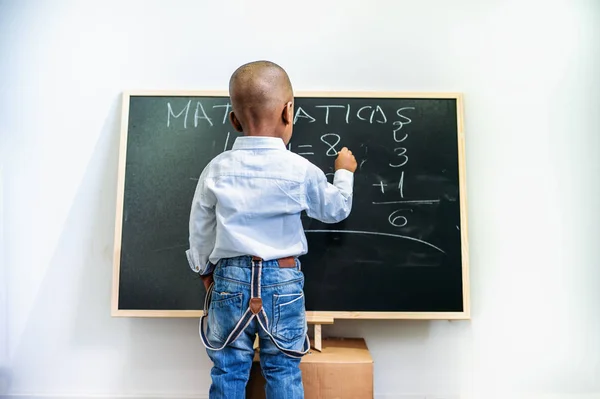 African girl in white shirt writes on the blackboard