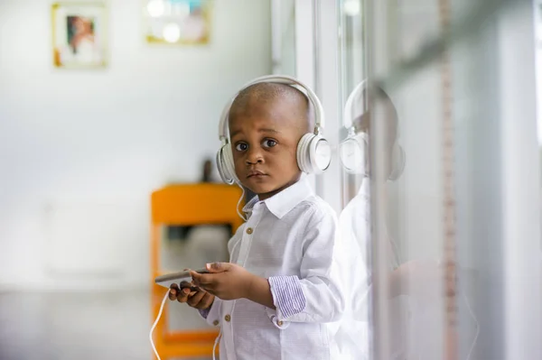 African child listens to music with mobile phone and headphones.