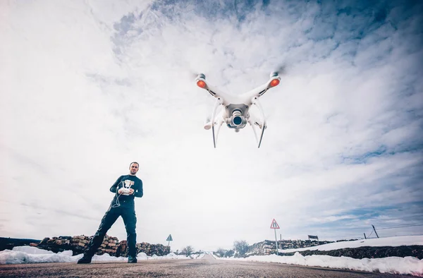 Man flying drone in snowy landscape.
