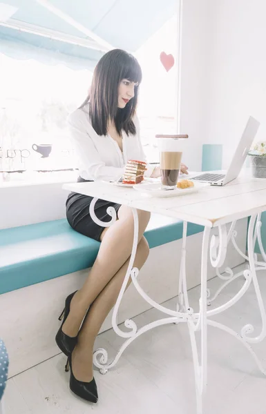 Brunette executive woman works with laptop in restaurant.