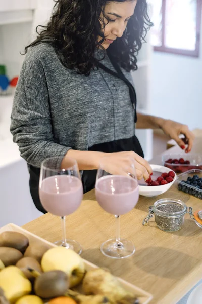 Woman making ecological shake of blueberries and raspberries