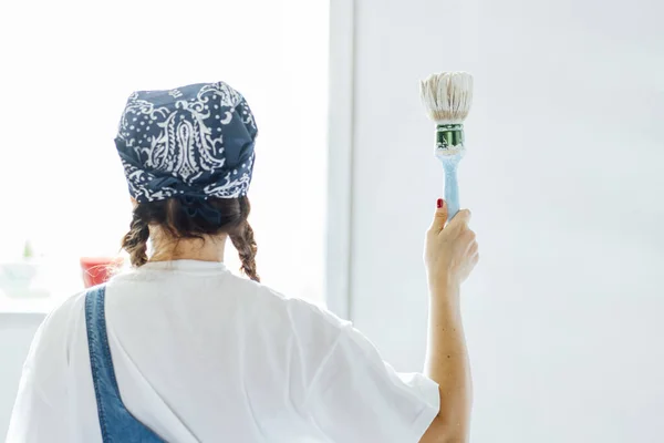 Young woman painting the walls of her home.