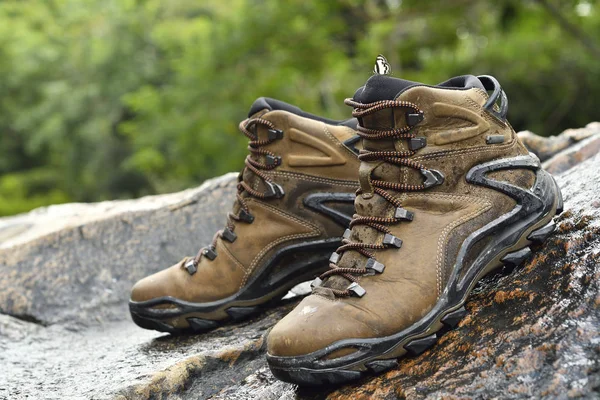 Pár bot na kameni. Hnědá kožená turistická bota na skále mezi lesy u řeky. — Stock fotografie