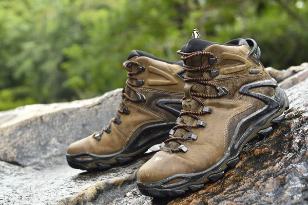 Par de sapatos em pedra. Bota de caminhada de couro marrom na rocha entre as florestas perto do rio . — Fotografia de Stock