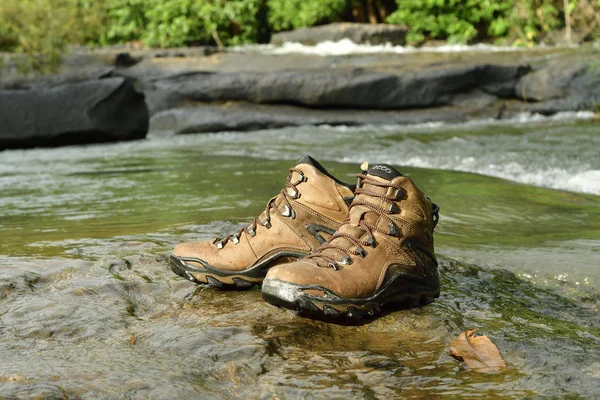 石の上の靴のペア 川の近くの森の中の岩の上に茶色の革のハイキングブーツ — ストック写真