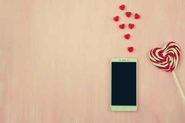 Valentines Day, heart shaped lollipops and phone, space for text — Stock Photo, Image