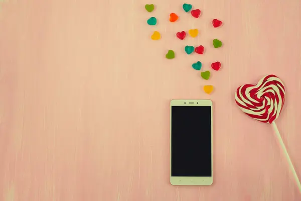 Valentines Day, heart shaped lollipops and phone, space for text — Stock Photo, Image