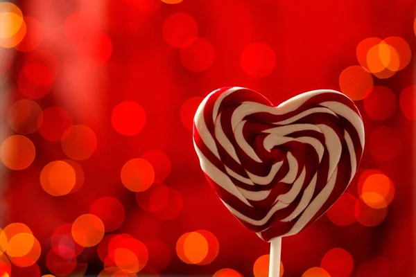Lollipop op een hart gevormd stok op een rode achtergrond. bokeh — Stockfoto