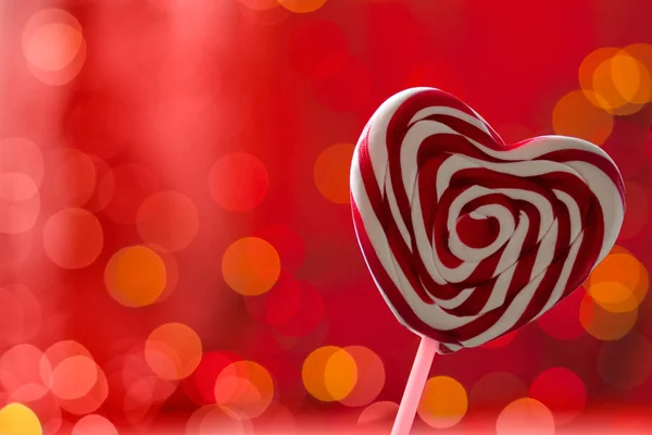 Lollipop op een hart gevormd stok op een rode achtergrond. bokeh — Stockfoto
