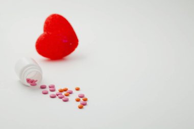 bir şişe ve kalp beyaz bir arka plan üzerine döktü hapları