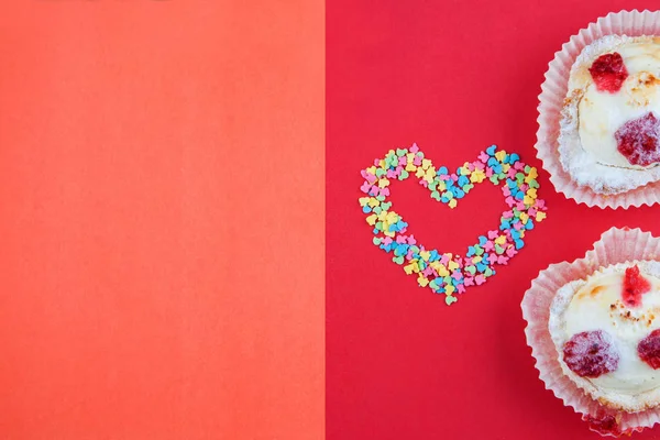 Kern gevormd met kleine snoep harten, roze, rood en blauw witte kleuren met twee taarten op rode achtergrond. Liefde, Valentijnsdag concept. Bovenaanzicht, kopie ruimte — Stockfoto