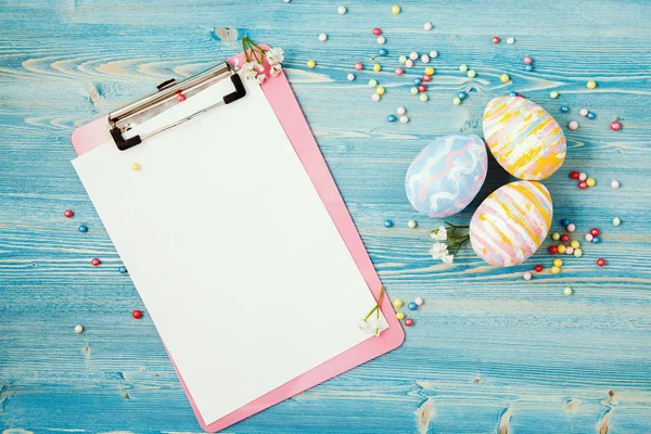 Veelkleurige Pasen eieren op een blauwe houten achtergrond met een tablet en een laptop achtergrond voor een briefkaart, Pasen concept, ruimte voor tekst. — Stockfoto