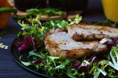 Kızarmış etli salata, otlar, koyu ahşap arka plan üzerinde biber. Kartpostal için arka plan.