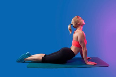 sarışın kız mavi yoga Mat mavi bir arka plan üzerinde uzanan devreye girer. Metin için yer