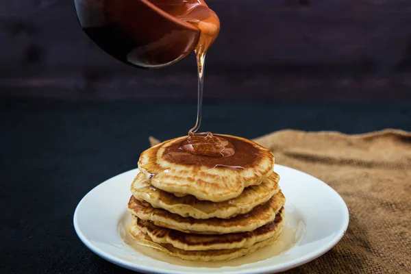 Pfannkuchen gießen Honig aus einer Schüssel auf einer dunklen Hintergrundkarte, Restaurant Rezeptkonzept. serviert in. — Stockfoto