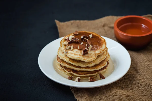 Appetitliche Pfannkuchen mit Honig und Nüssen auf einem dunklen Tisch. Menü, Restaurant Rezeptkonzept. serviert in — Stockfoto