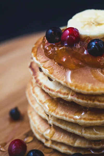 Pfannkuchen mit Honig, Bananen, Marmelade und Beeren auf einem hölzernen Teller Menü, Restaurant Rezeptkonzept. serviert in — Stockfoto