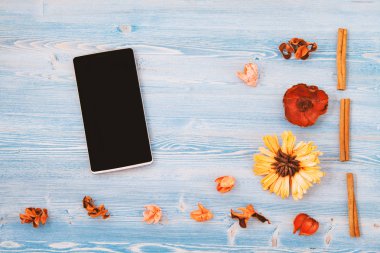 Kırmızı ve sarı çiçekler, defter ve ahşap arka plan mavi bir smartphone. Doku ve arka plan. Kavramı bir kartpostal için