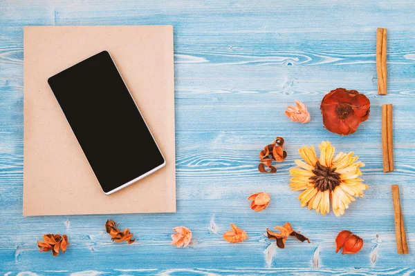 Oranje en gele bloemen, laptop en smartphone op een blauwe achtergrond van houten. Textuur en achtergrond. Concept voor een briefkaart — Stockfoto