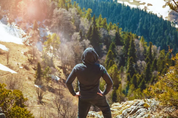 the guy the traveler stands on top of the mountain. .View from back of the tourist traveler on background mountain