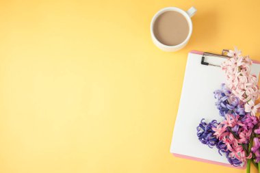 Eflatun çiçekler, kahve ve not etmek üstünde sarı bir arka plan bahar, yaz konsepti düz üst yatıyordu boşaltmak görüntülemek