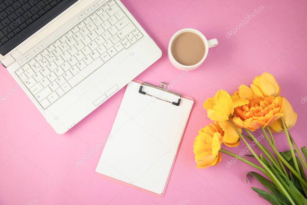 yellow tulips, laptop and notepad on a lilac background Spring, summer concept Flat lay Top view Copyspace