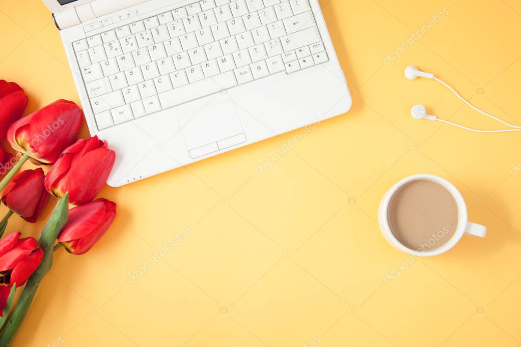 red tulips, laptop and coffee on a yellow background Spring, summer concept Flat lay Top view