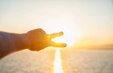 Eller streç denizin üzerinde güneşin doğru mans. Katlanmış parmaklarımın arasından günbatımında bir adam görünüyor