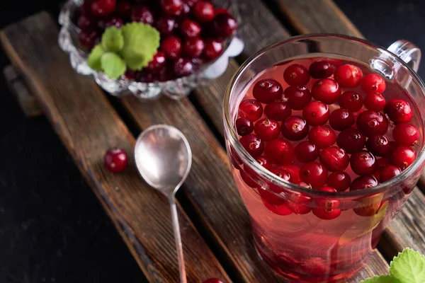 cranberry juice with honey in a cup, cranberries in sugar. On a dark wooden background