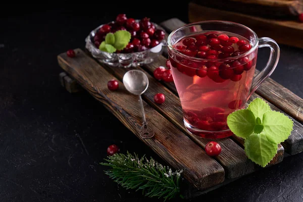 cranberry juice with honey in a cup, cranberries in sugar. On a dark wooden background Copy space