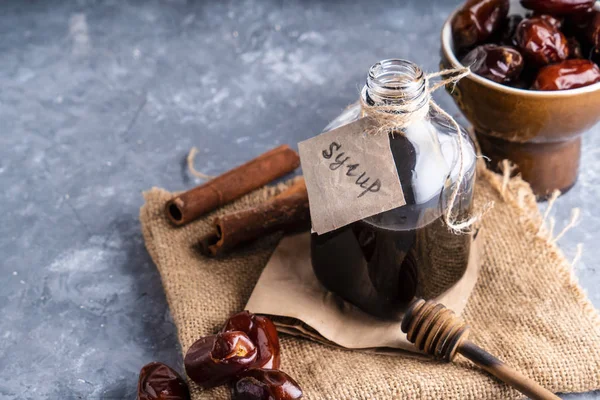 Homemade dates syrup in glass bottle on gray stone table. Alternative food and drink Trend food 2020. Copy space.