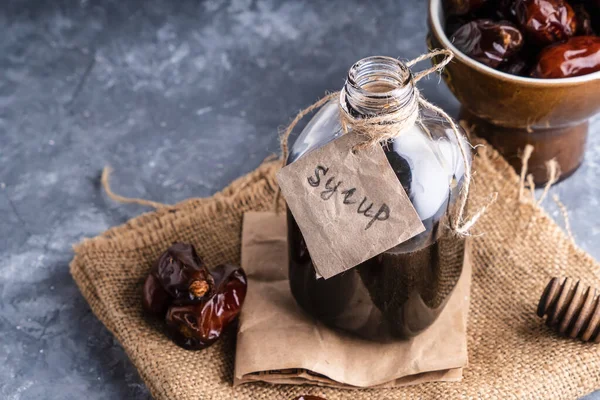 Homemade dates syrup in glass bottle on gray stone table. Alternative food and drink Trend food 2020. Copy space.