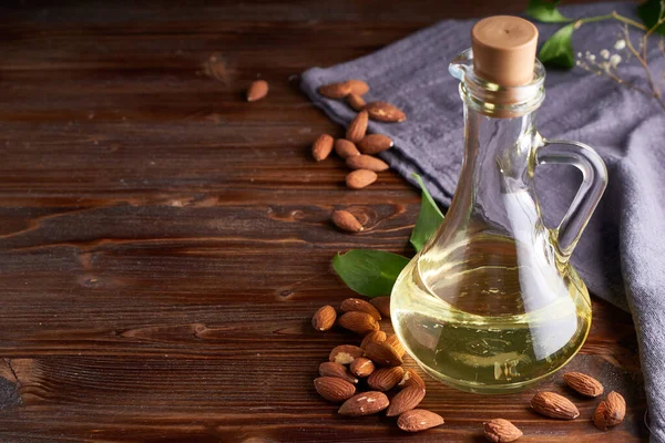 Healthy Almond oil in glass bottle. Dark wooden background Copy space