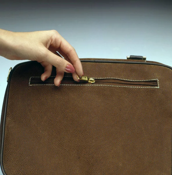 hand pull a zipper to close a handbag