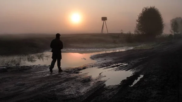 Gündoğumu zaman insan siluet yanındaki çamurlu yol Biebrza, Polonya