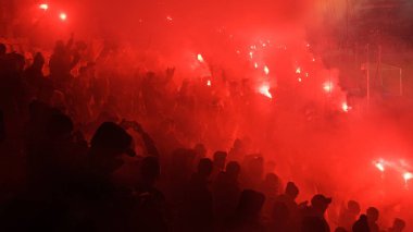 KRAKOW, POLAND-DECEMBER 13, 2017: Polish soccer fans lighting smoke flares at Cracovia Stadium, during the Polish Premiere League match Cracovia vs Wisla Krakow, in Krakow clipart