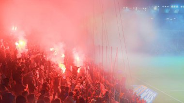 KRAKOW, POLAND-DECEMBER 13, 2017: Polish soccer fans lighting smoke flares at Cracovia Stadium, during the Polish Premiere League match Cracovia vs Wisla Krakow, in Krakow clipart