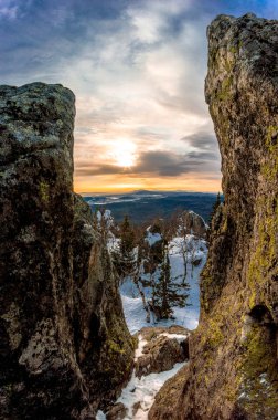 Kayaların üzerinden güneş parlar. Dağların soğuk kışın daha sıcak görünüyor. Hava rüzgarlı.