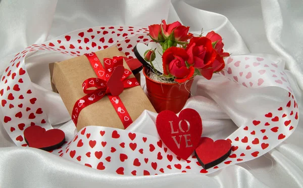 red and white otkrtyka with hearts, a bucket of roses, a gift and ribbons for Valentine's Day