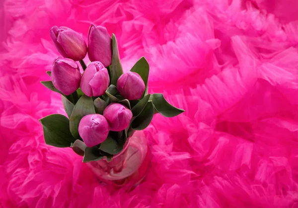 a bouquet of pink spring live tulips against the background of a pink tulle skirt with frills