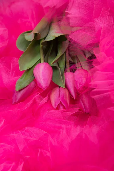 a bouquet of pink spring live tulips against the background of a pink tulle skirt with frills