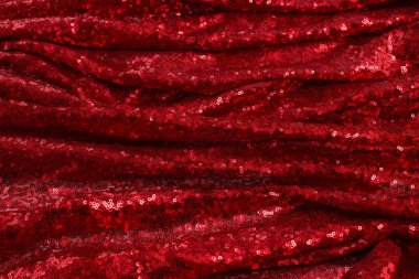 Küçük yuvarlak pullu parlak kırmızı kumaş, Sevgililer Günü 'nde dalgalarla serilmiş metalik parıltı.