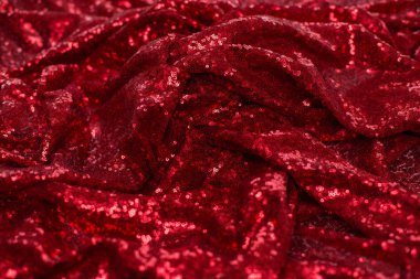 Küçük yuvarlak pullu parlak kırmızı kumaş, Sevgililer Günü 'nde dalgalarla serilmiş metalik parıltı.