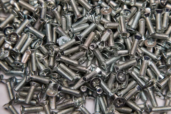 M6 metal screws galvanized white in bulk closeup in the studio